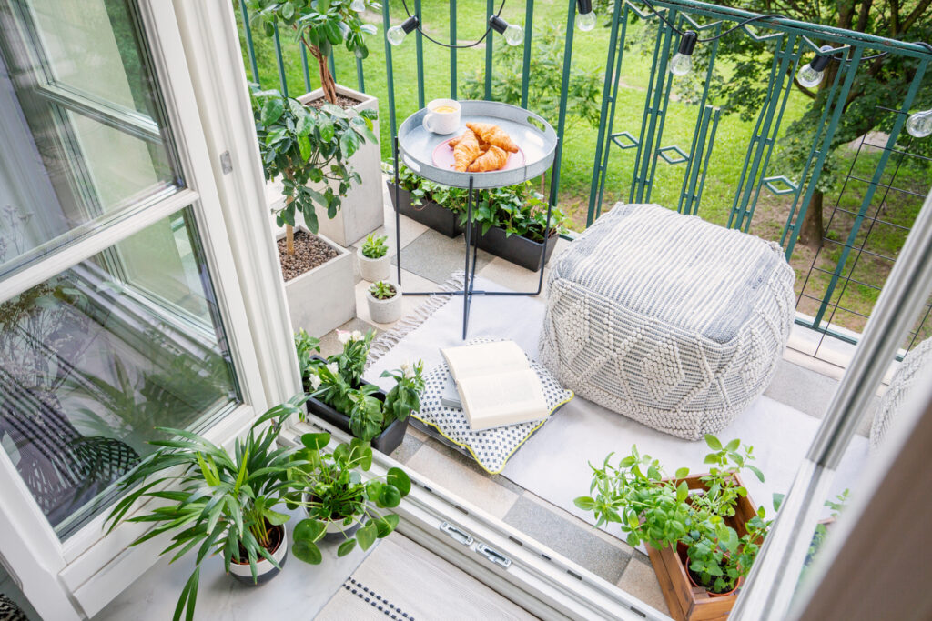 Pohľad zhora na štýlový balkón s rastlinami, pouf stôl s raňajkami