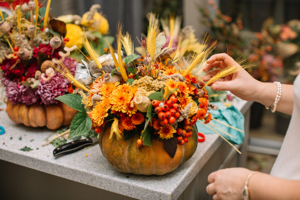 žena dekoruje jesenné plody do tekvice 