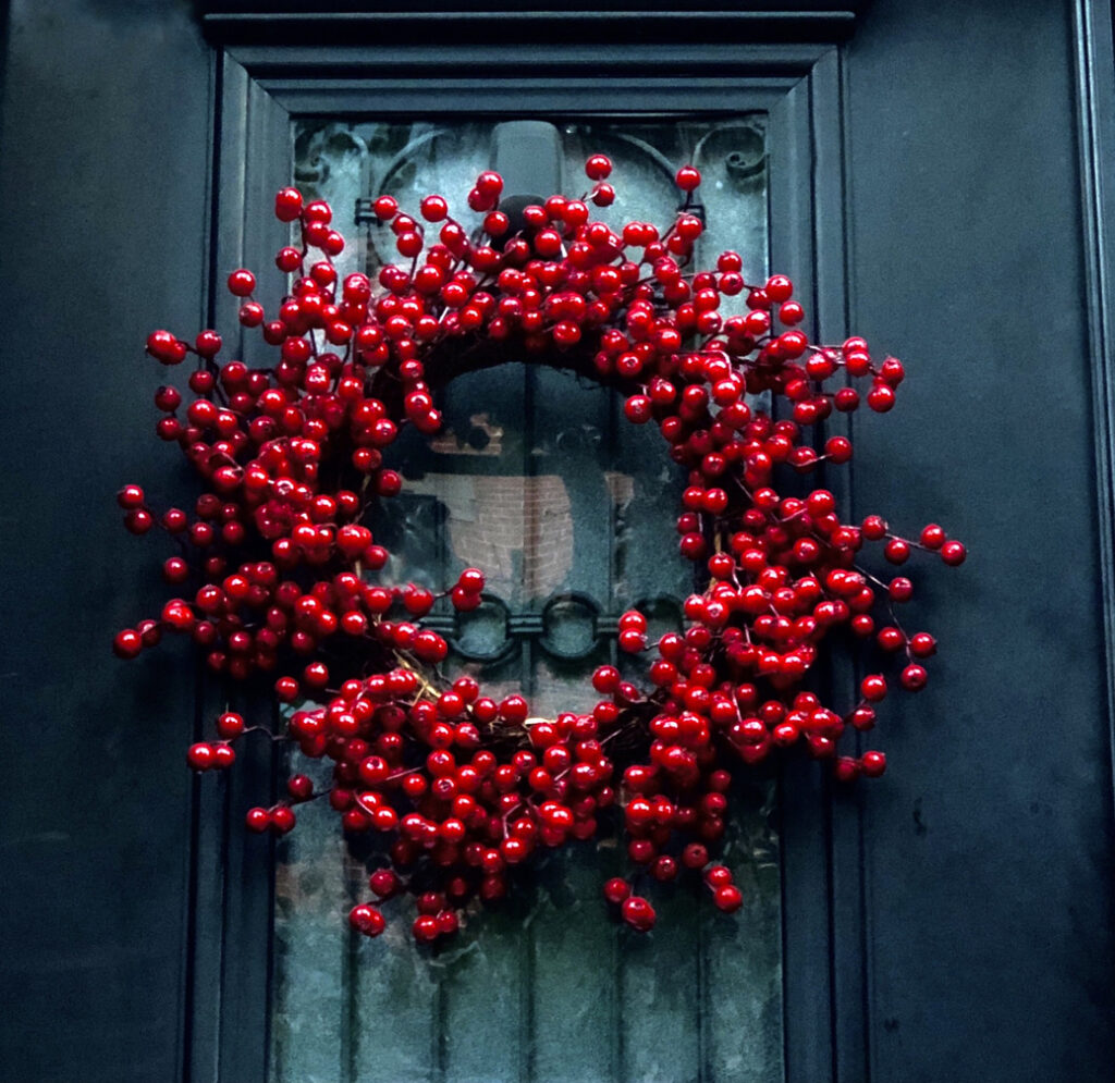 Umelý červený bobuľový veniec zdobí sivé dvere