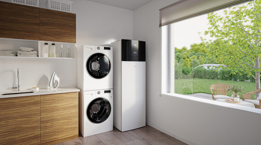Interiérová jednotka tepelného čerpadla Daikin Altherma 4 vedľa práčky a sušičky v modernej technickej miestnosti s výhľadom do záhrady.