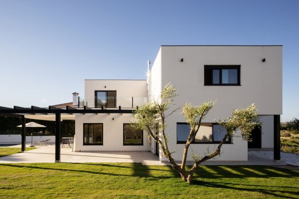 Moderný rodinný dom s bielou fasádou v zelenej záhrade – ukážka čistej bielej fasády Baumit Crystal.