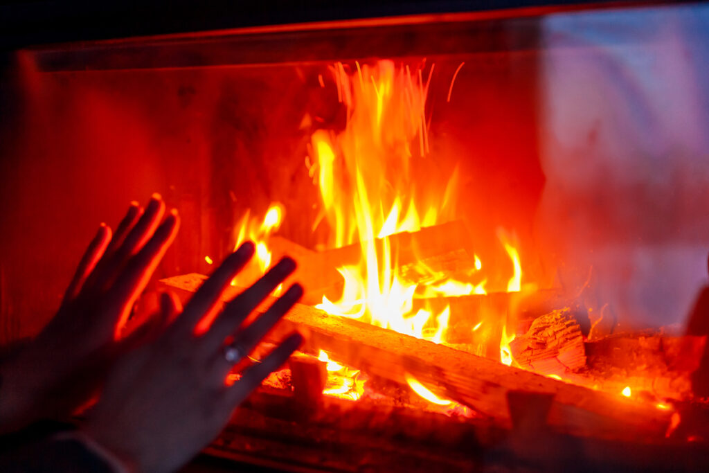 ruky zohrievajúce sa pri horiacom ohni v krbe