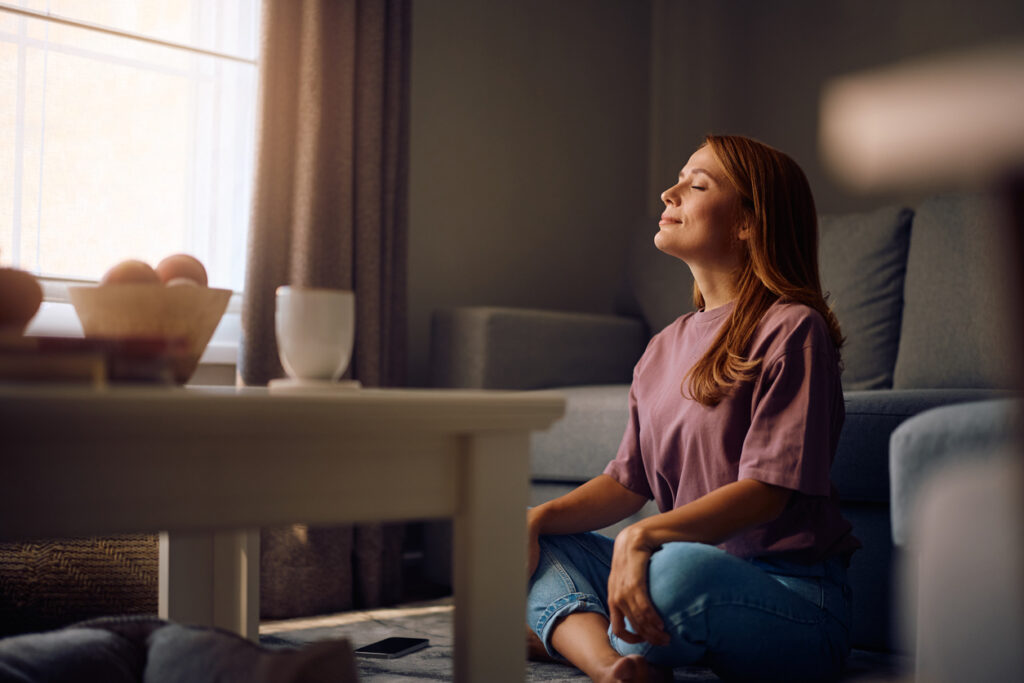 žena meditujúca v obývačke počas relaxu doma
